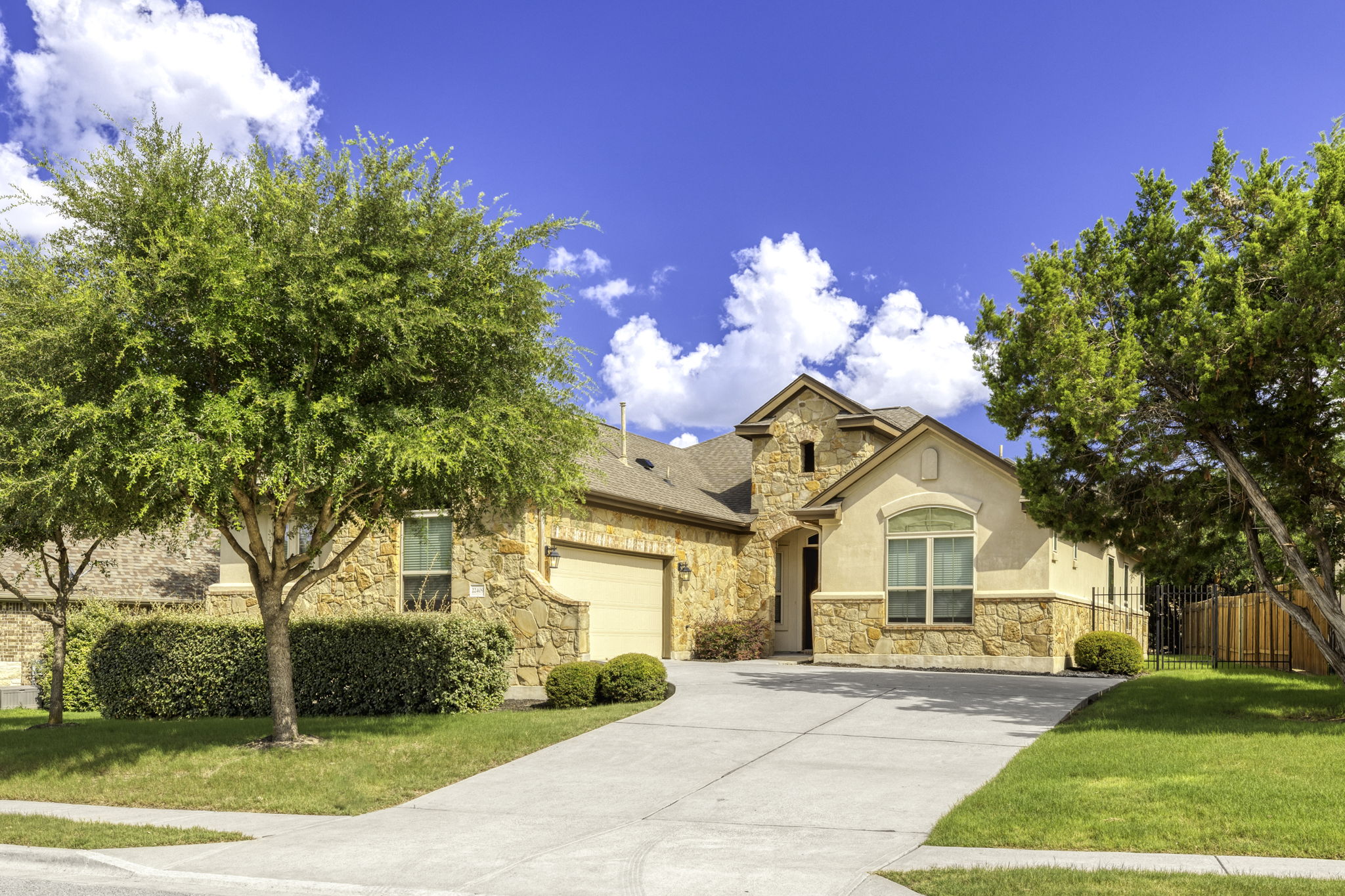 22409 Rock Wren Road Spicewood, TX 78669 - Photo 1 of 1 View of front of home featuring stone siding, concrete driveway, roof with shingles, and stucco siding