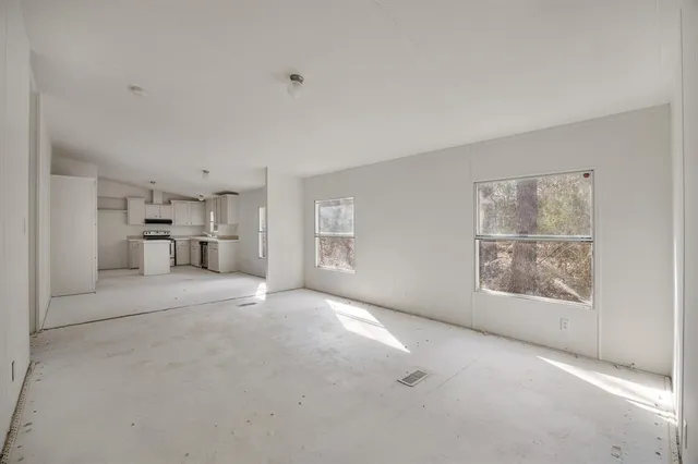 a view of empty room with a kitchen and refrigerator
