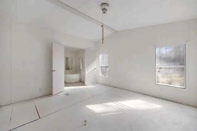 a view of an empty room with a window and a bathroom