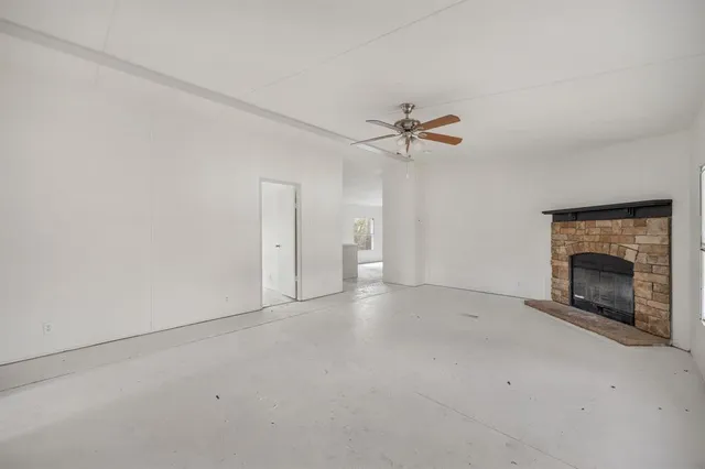 an empty room with fan and a fireplace