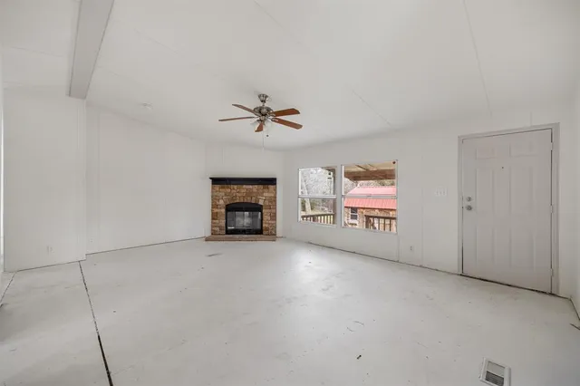 an empty room with windows and fireplace