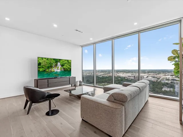 a living room with furniture a flat screen tv and a large window