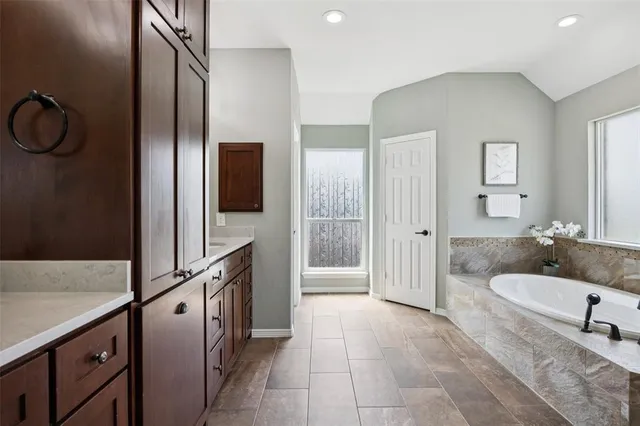 a bathroom with a tub a mirror and a shower