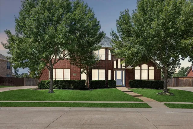 a front view of a house with a garden and trees