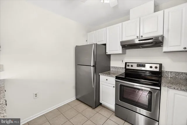 a kitchen with granite countertop white cabinets and stainless steel appliances