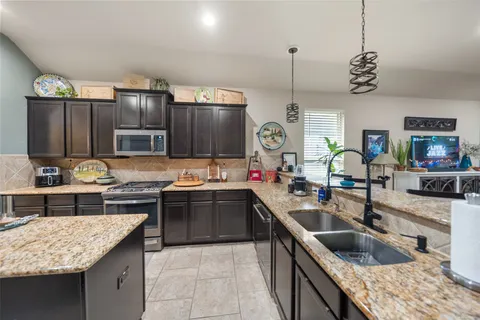 a kitchen with stainless steel appliances granite countertop a stove a sink and a refrigerator