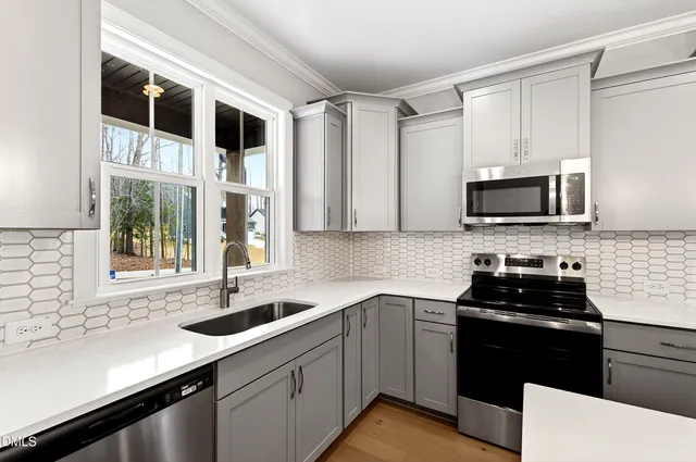 a kitchen with stainless steel appliances kitchen island granite countertop a stove a sink dishwasher a refrigerator and a fireplace with wooden floor