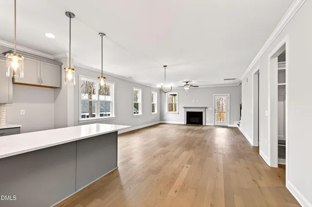 a view of an empty room with kitchen and window