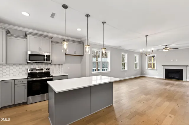 an empty room with windows fireplace and a kitchen
