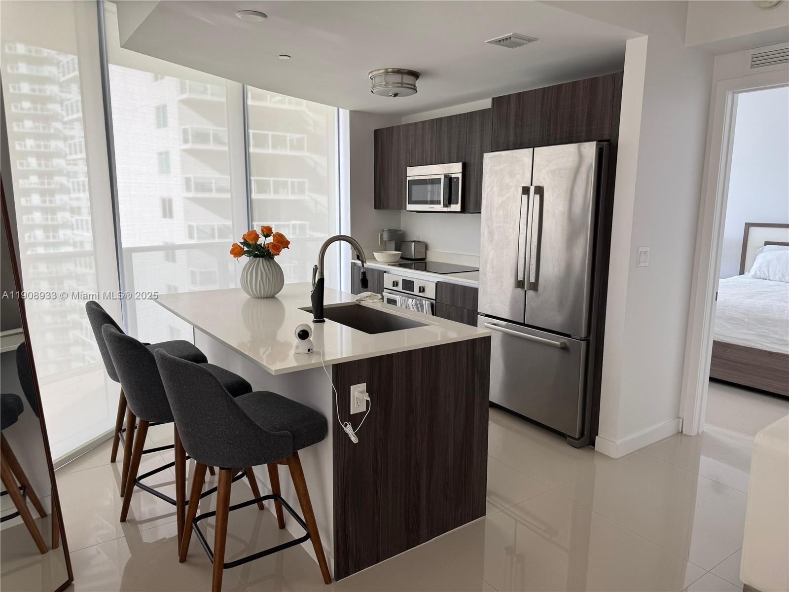 488 Northeast 18th Street, Unit 2701 Miami, FL 33132 - Photo 6 of 70 a kitchen with a refrigerator a table and chairs in it