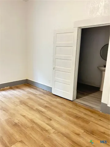 a view of an empty room with wooden floor and closet