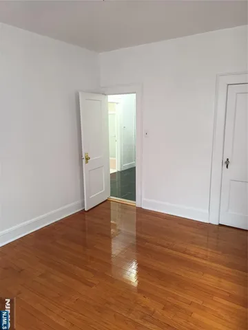 a view of an empty room with wooden floor and closet