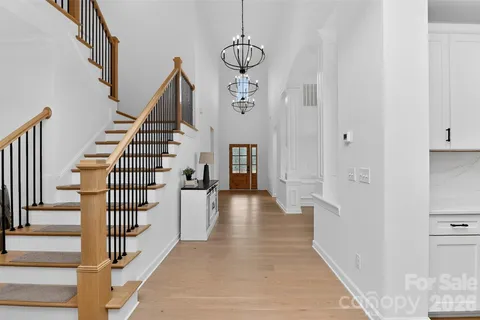 a view of a hallway with wooden floor windows and a chandelier