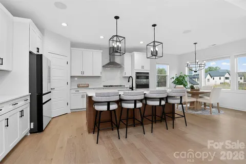 a kitchen with stainless steel appliances a dining table chairs stove and cabinets