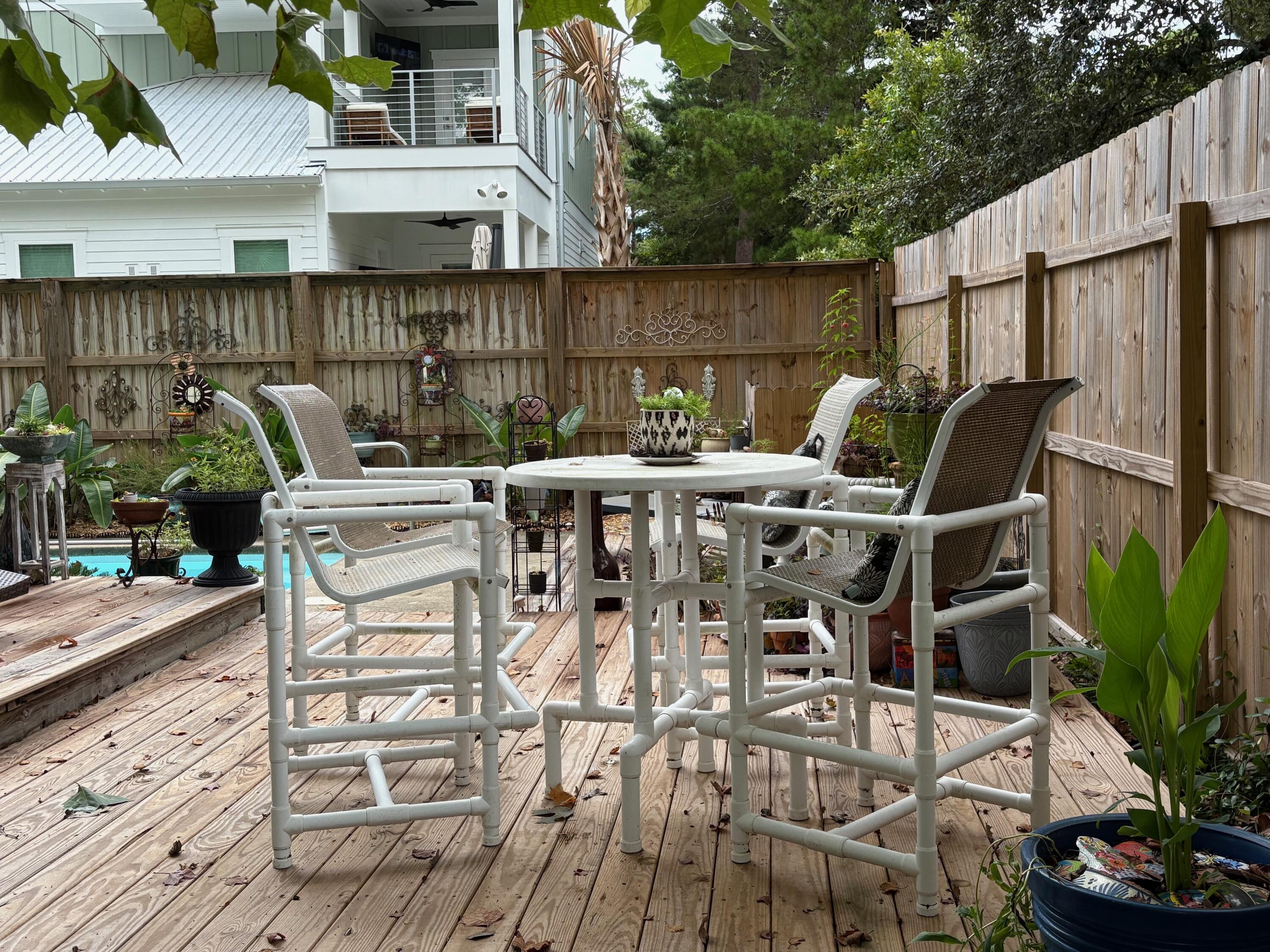 335 Acacia Street Santa Rosa Beach, FL 32459 - Photo 18 of 36 a view of a patio with table and chairs potted plants with wooden floor
