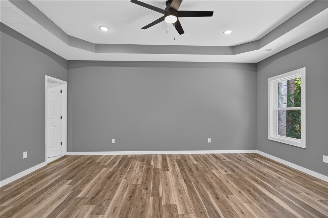 223 Maple Drive Anderson, SC 29621 - Photo 18 of 45 A generously sized primary bedroom features a striking tray ceiling and durable laminate flooring.