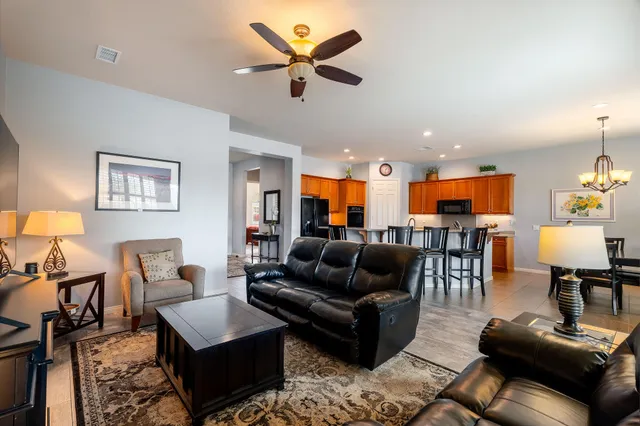 a living room with furniture kitchen view and a chandelier