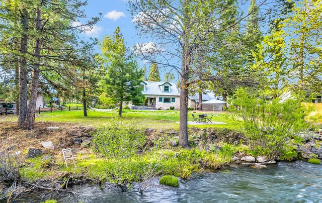 a view of a house with a big yard and large trees