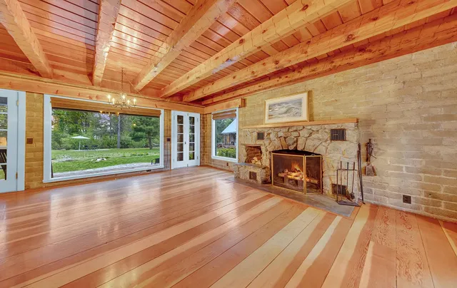 a view of an empty room with wooden floor fireplace and a window