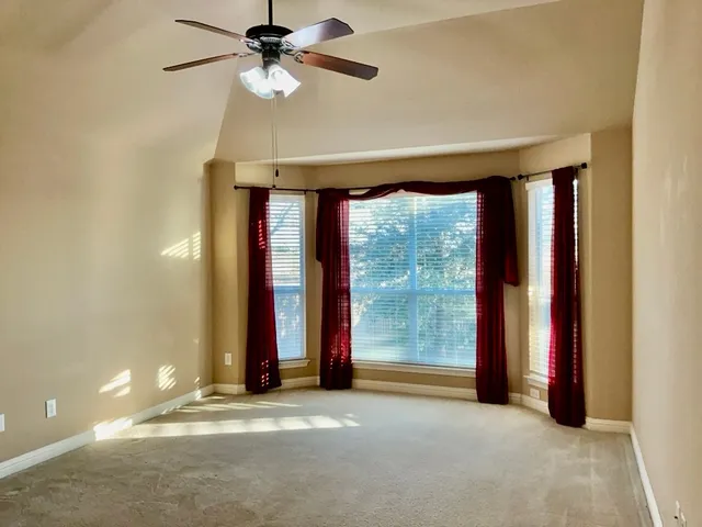 a view of a room with large windows and ceiling fan