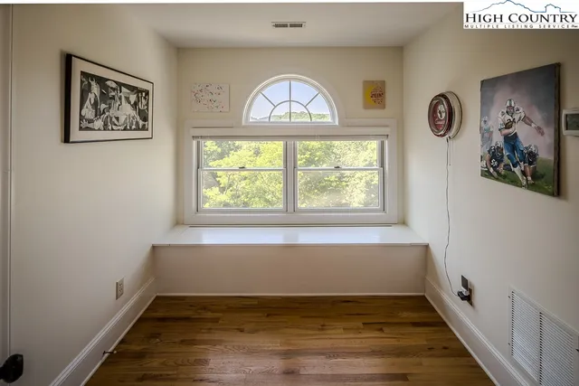 an empty room with wooden floor and windows