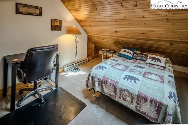 a bedroom with a bed a desk and chair with wooden floor