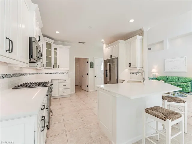 a large white kitchen with a refrigerator a stove a sink dishwasher and white cabinets with wooden floor