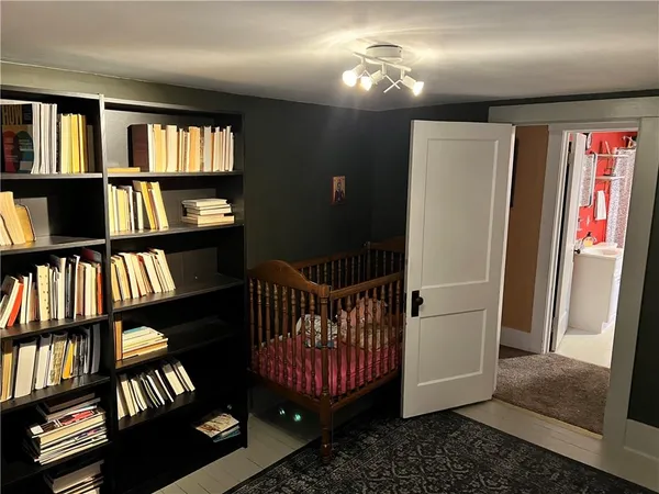 a bedroom with a bed a standing fan and a bookshelf