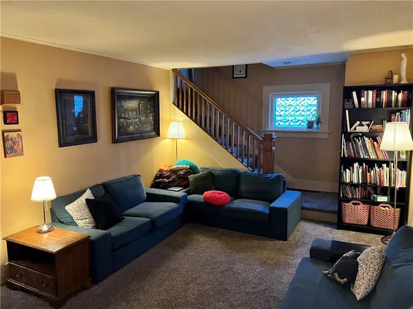 a living room with furniture book shelf and wooden floor