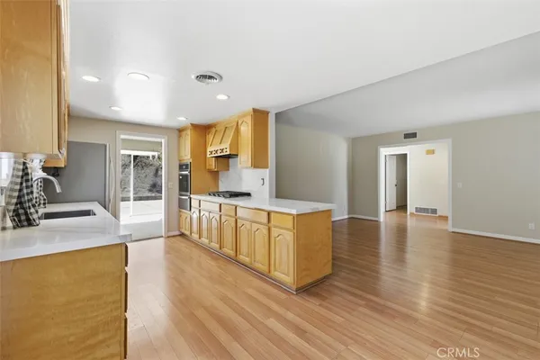 a large kitchen with kitchen island a sink a stove a refrigerator and white cabinets with wooden floor