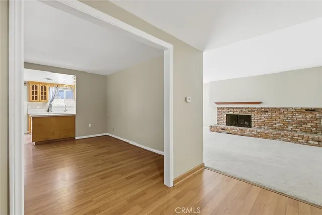 an empty room with wooden floor a fireplace and windows