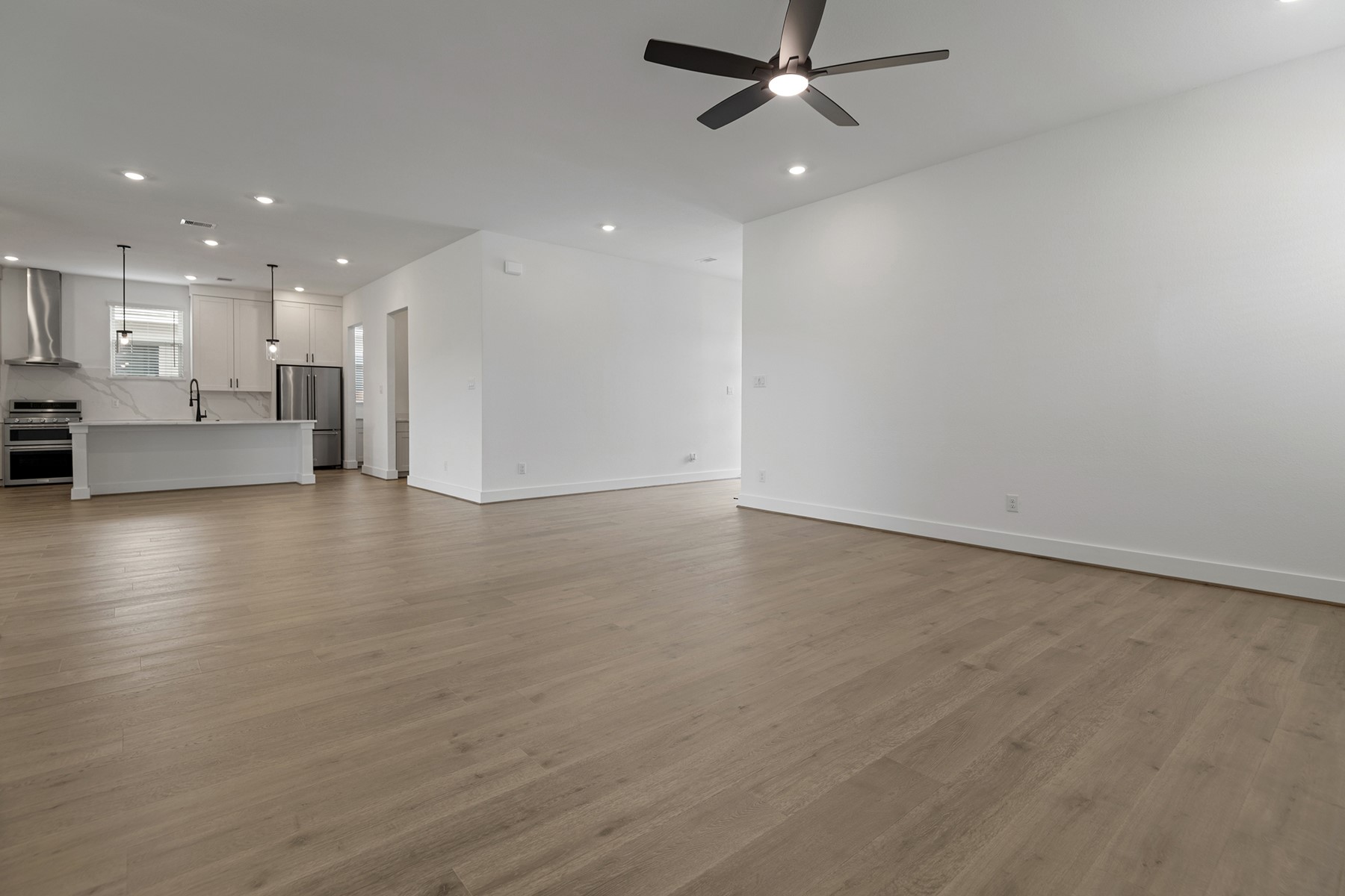 1911 Drover Lane Rosenberg, TX 77471 - Photo 5 of 22 an empty room with wooden floor a ceiling fan and kitchen view