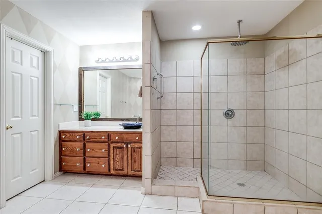 a bathroom with a granite countertop sink a mirror and shower