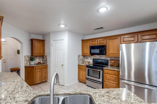 a kitchen with stainless steel appliances granite countertop a refrigerator and a stove top oven