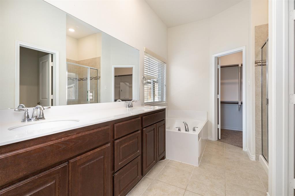516 Maverick Street Anna, TX 75409 - Photo 20 of 28 a spacious bathroom with a double vanity sink a large mirror and a bathtub