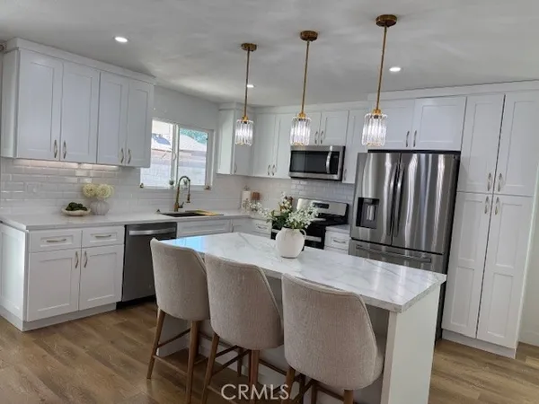 a kitchen with stainless steel appliances granite countertop a stove a sink a refrigerator a center island a dining table and chairs