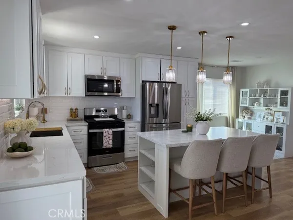 a kitchen with a refrigerator a stove a sink and chairs