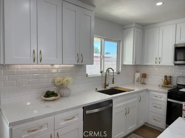 a kitchen with stainless steel appliances granite countertop white cabinets a sink and dishwasher