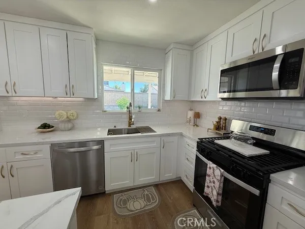a kitchen with stainless steel appliances a sink a stove a microwave and cabinets