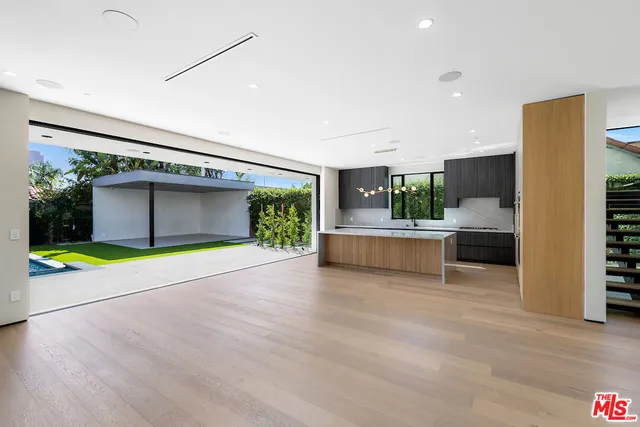 a view of an empty room with a kitchen and window