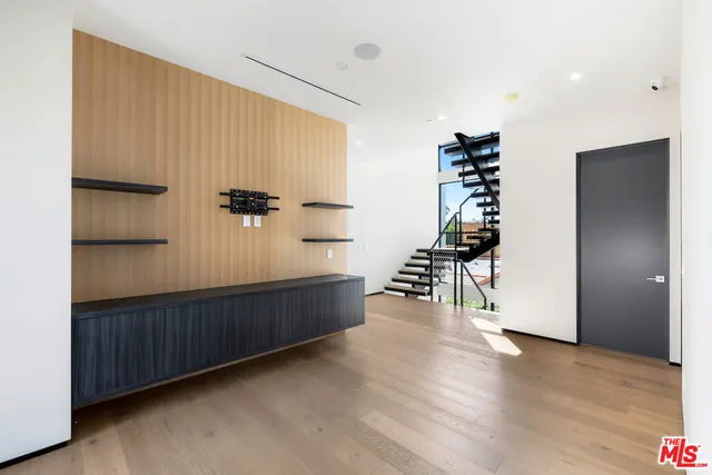 a view of an empty room with wooden floor and stairs