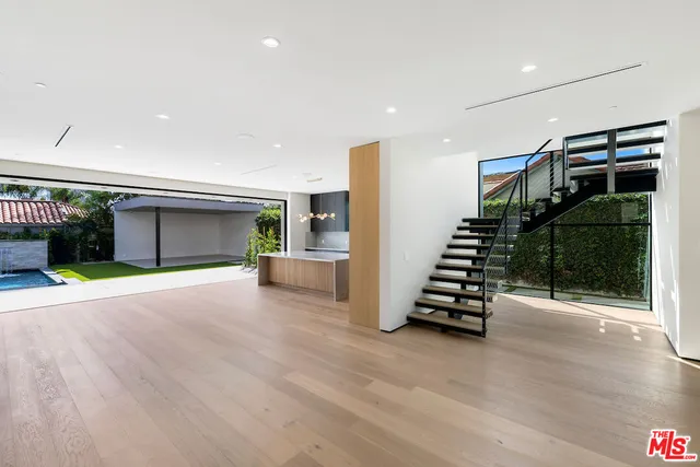 a view of an empty room with wooden floor and stairs