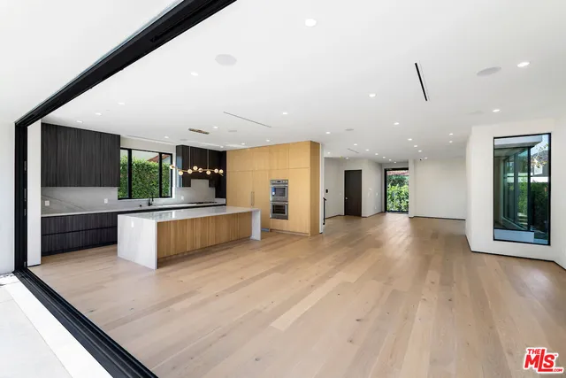 a large kitchen with stainless steel appliances a large counter top a stove and a wooden floors