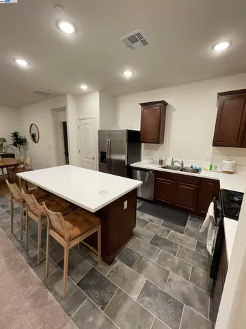 a kitchen with stainless steel appliances kitchen island granite countertop a sink a stove a counter top space and cabinets