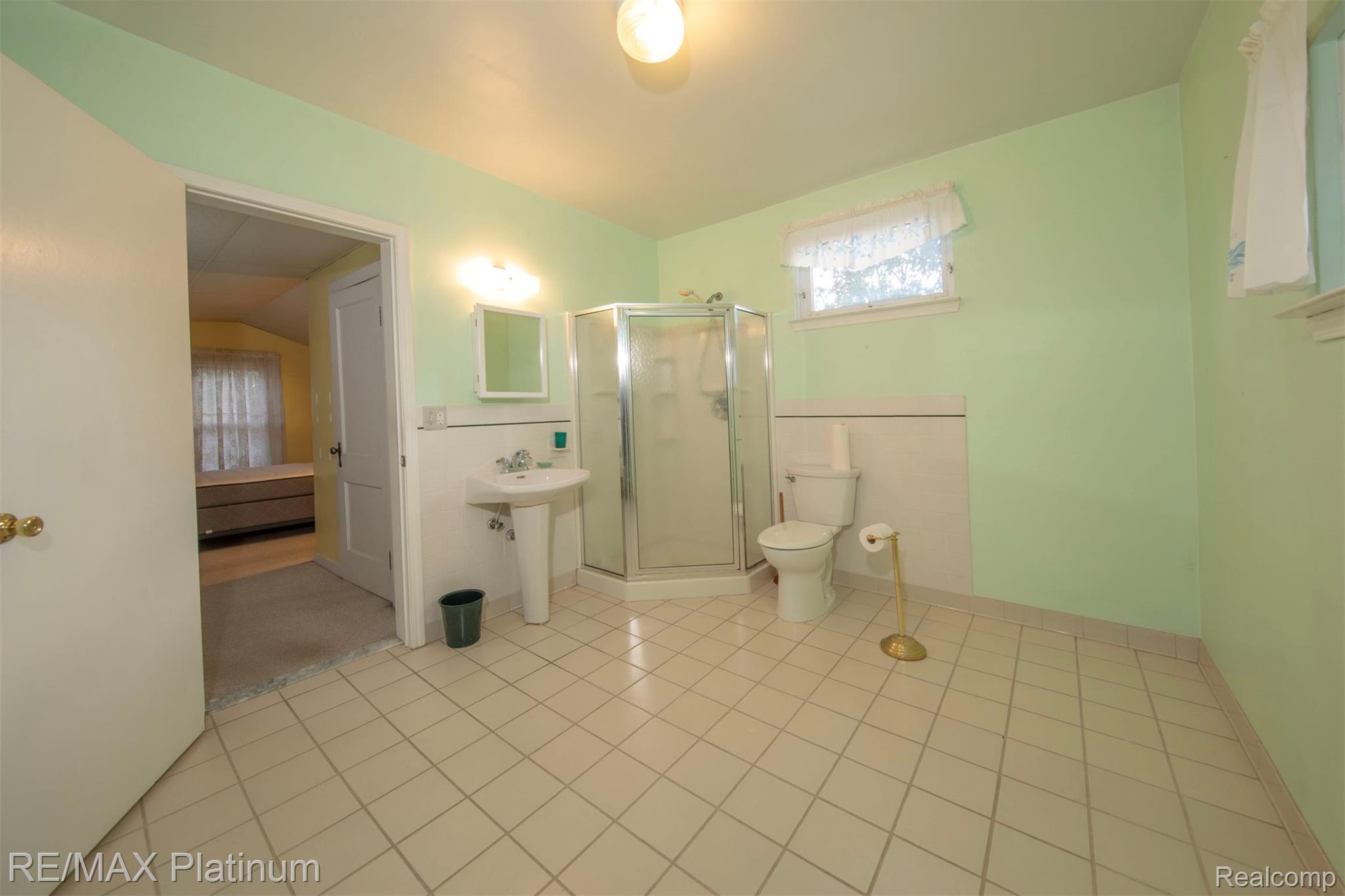 18696 Inkster Road Redford, MI 48240 - Photo 12 of 14 Pedestal sink with mirror, glass-enclosed corner shower, and tiled flooring