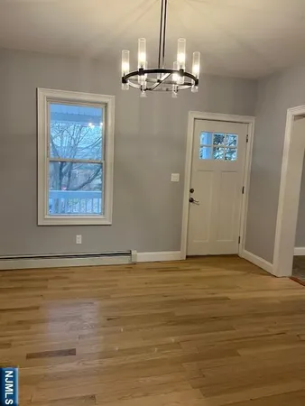 a view of an empty room with wooden floor and a chandelier