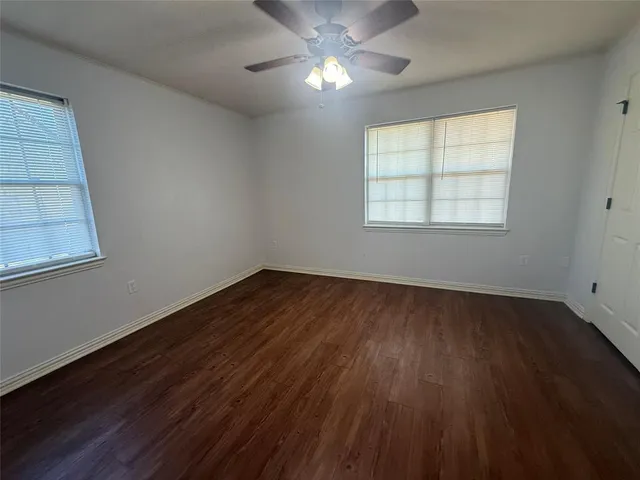 a view of empty room with wooden floor and fan