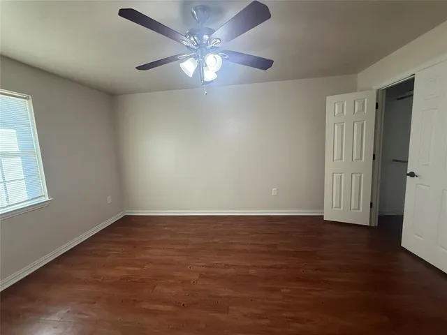 an empty room with wooden floor and a ceiling fan