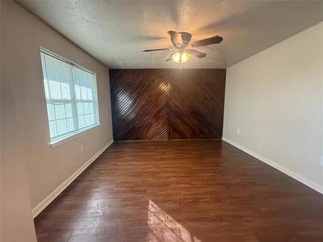 an empty room with windows and fan chandelier