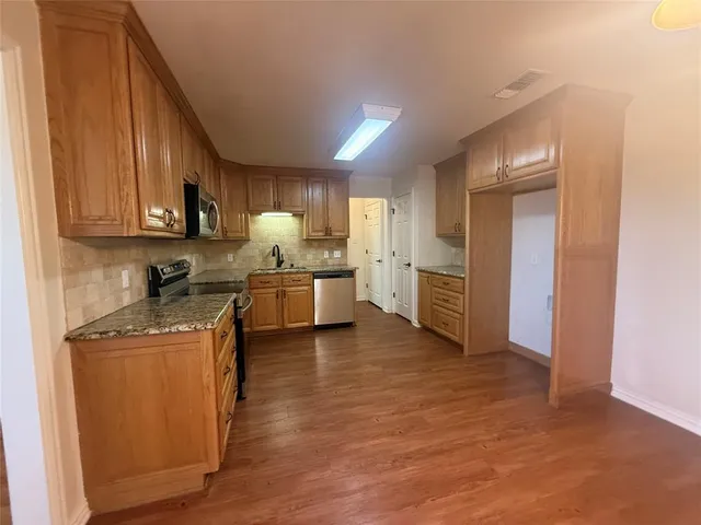 a kitchen with stainless steel appliances granite countertop a stove a sink and a refrigerator